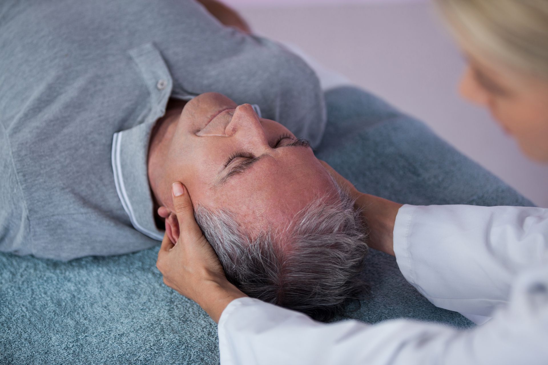 A man is getting a head massage from a woman.