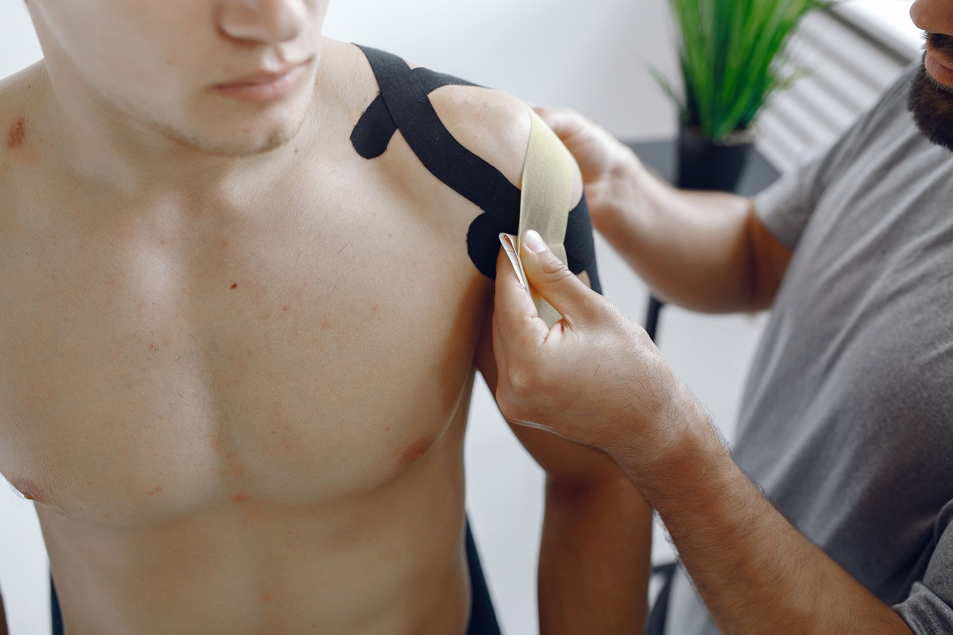 a shirtless man is getting kinesio tape on his shoulder