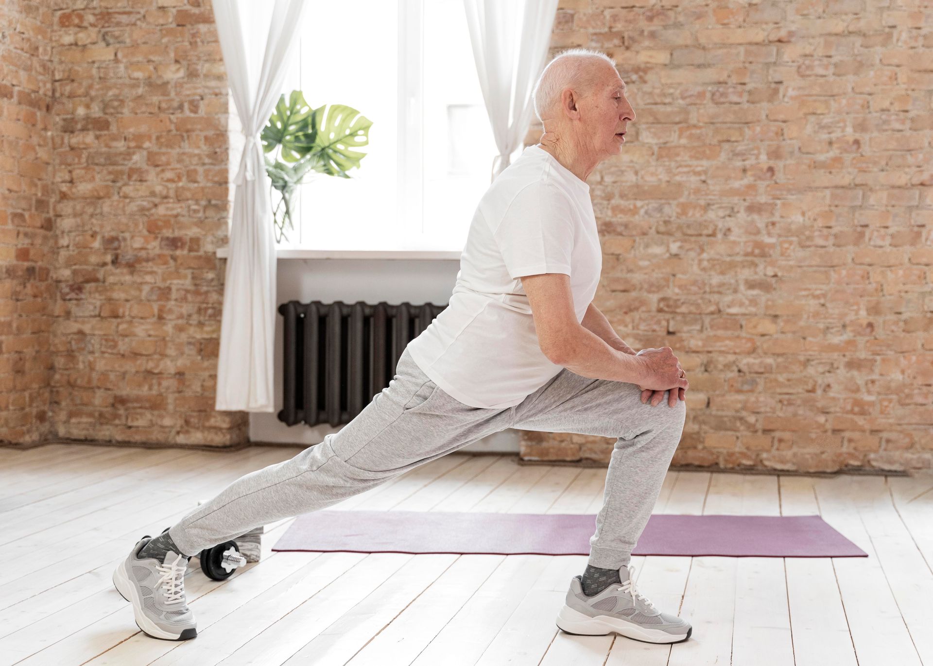 an older man stretches his legs on a yoga mat