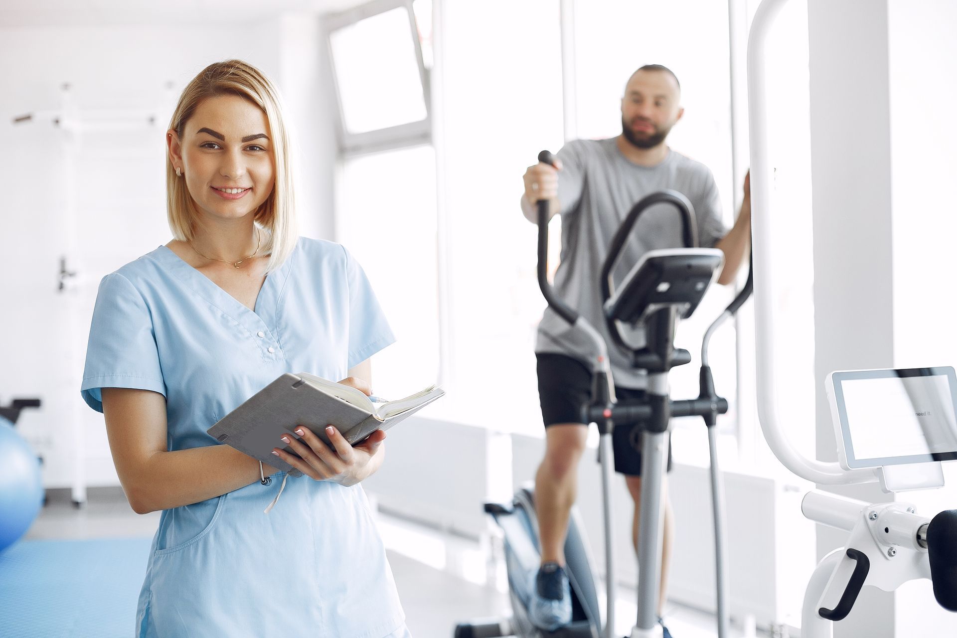a nurse is holding a book in front of a man on an elliptical