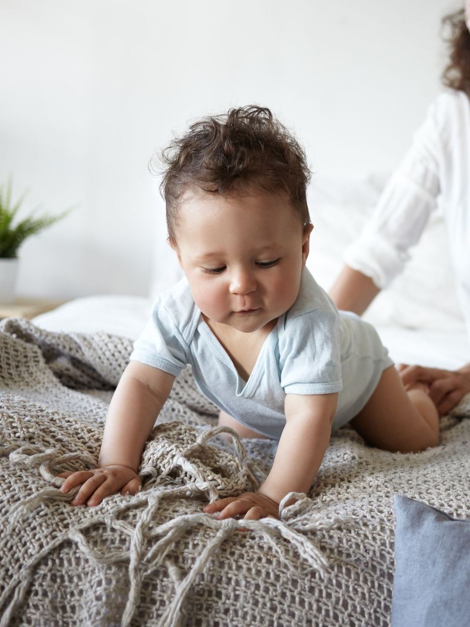 a baby is crawling on a bed next to a woman