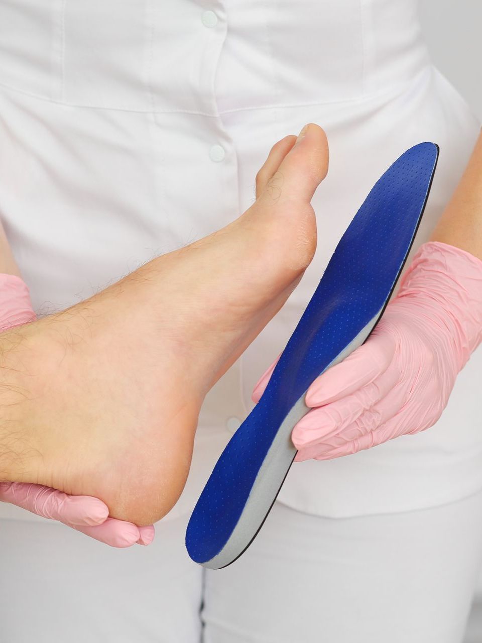 a person 's foot is being examined by a nurse wearing pink gloves