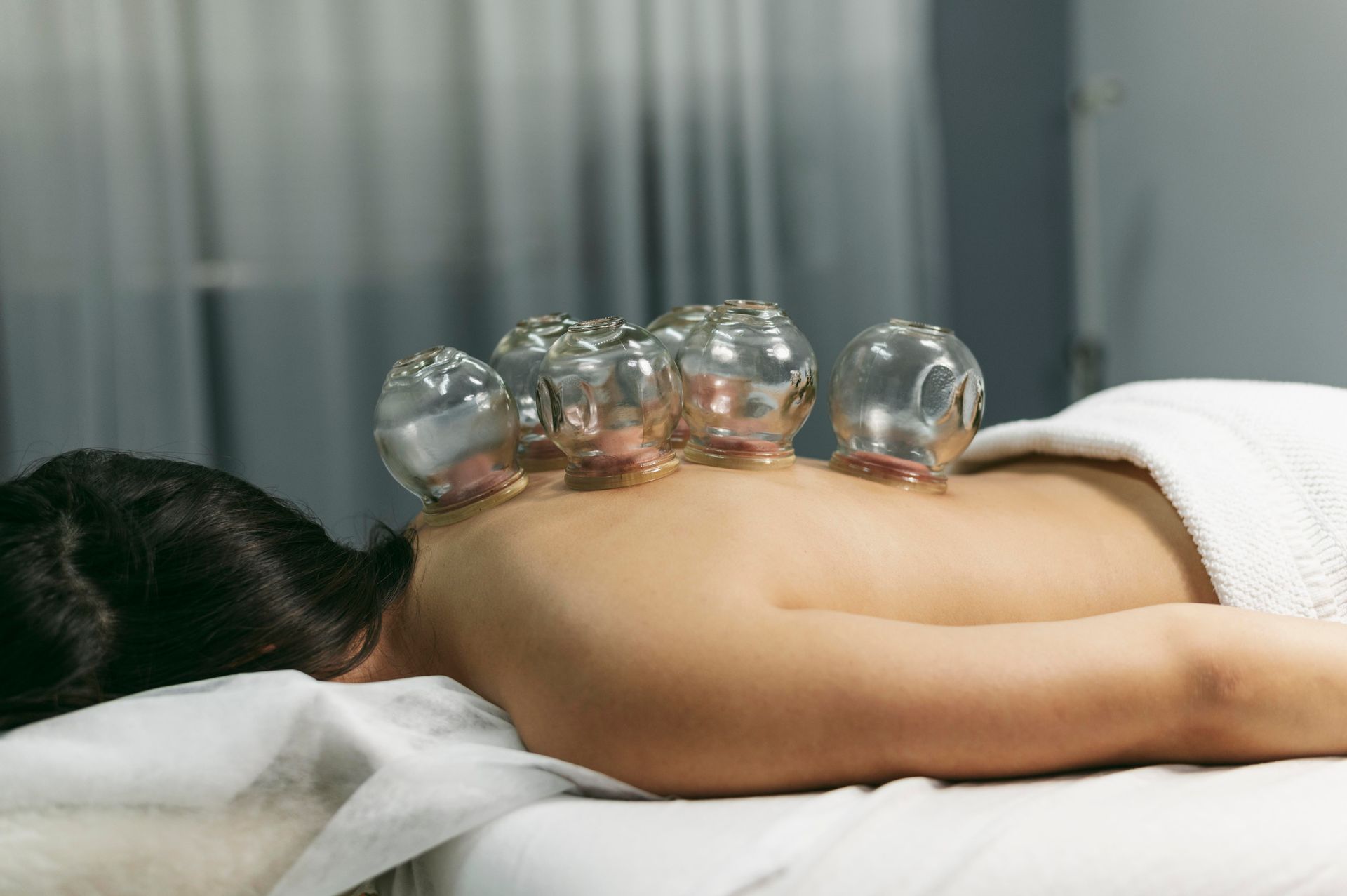 a woman is laying on a table with clear cups on her back