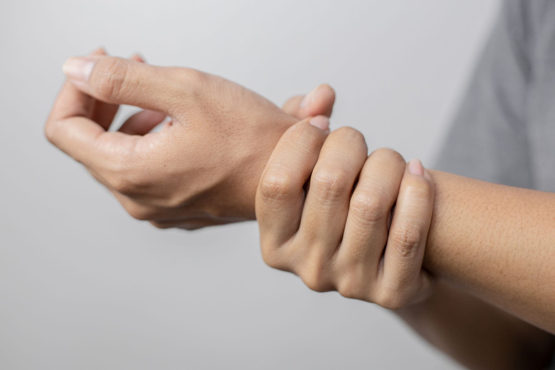 Person holding their wrist, possibly due to pain or discomfort, with fingers and thumb gripping.