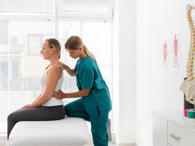 a woman is sitting on a bed while a nurse examines her back