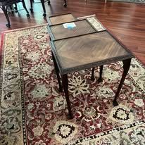 Three vintage nesting tables on a patterned rug with a floral design.