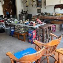 Garage sale with tables, chairs, and items for sale, with a blue cooler.