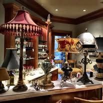 Antique lamps on a counter. The lamps have ornate bases and shades with red, gold, and cream colors.