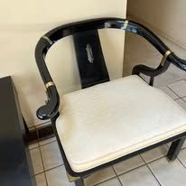 Black and gold chair with white cushion on a tiled floor.