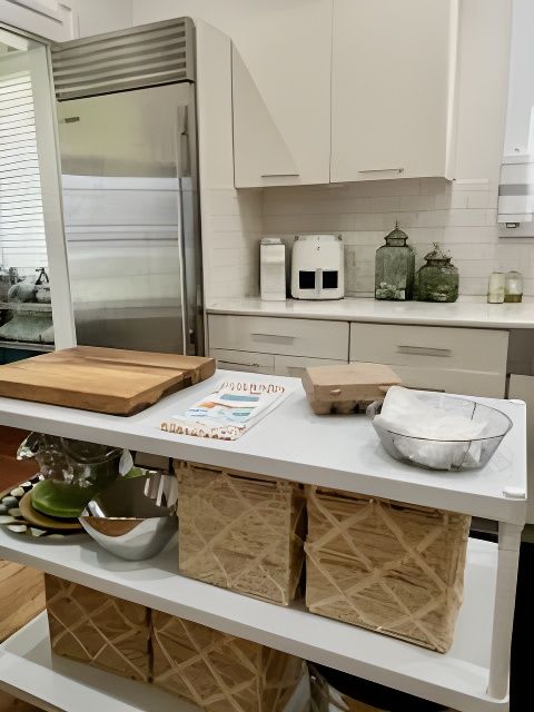Kitchen counter with storage baskets and food items, including a cutting board and egg carton, near a refrigerator.
