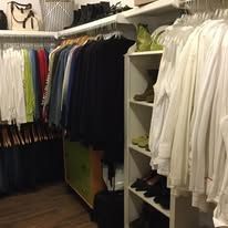 Closet with hanging clothes; white shirts, jackets, and other garments in a brightly lit room.