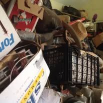 Messy storage room with boxes, baskets, and various items piled together.
