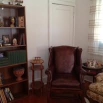 Living room with bookcase, armchair, side table, and a window.