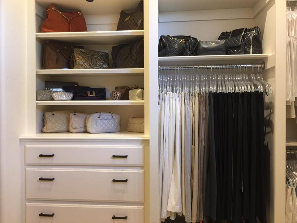 Built-in closet with shelves of handbags and drawers. Right side holds hanging clothes, mostly light/dark pants.