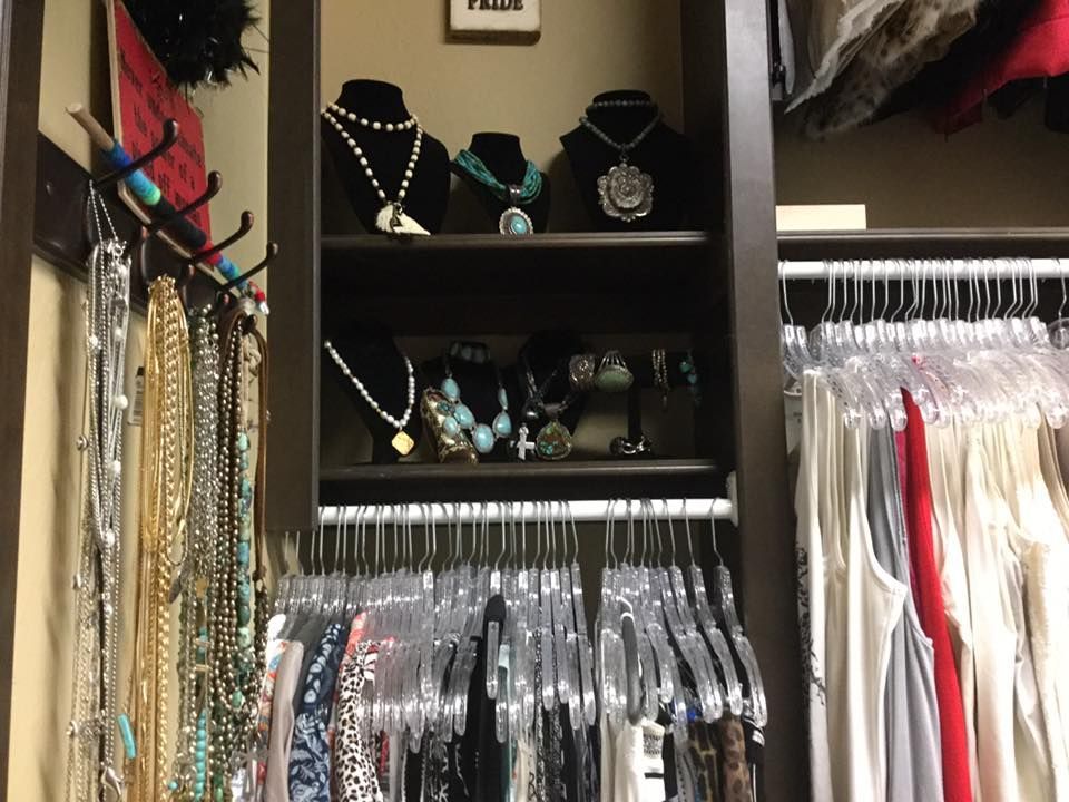 Closet with hanging necklaces, shelves of jewelry, and hanging clothes.