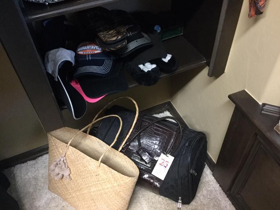 A closet shelf with shoes, bags, and a straw tote bag on the floor, next to a brown dresser.