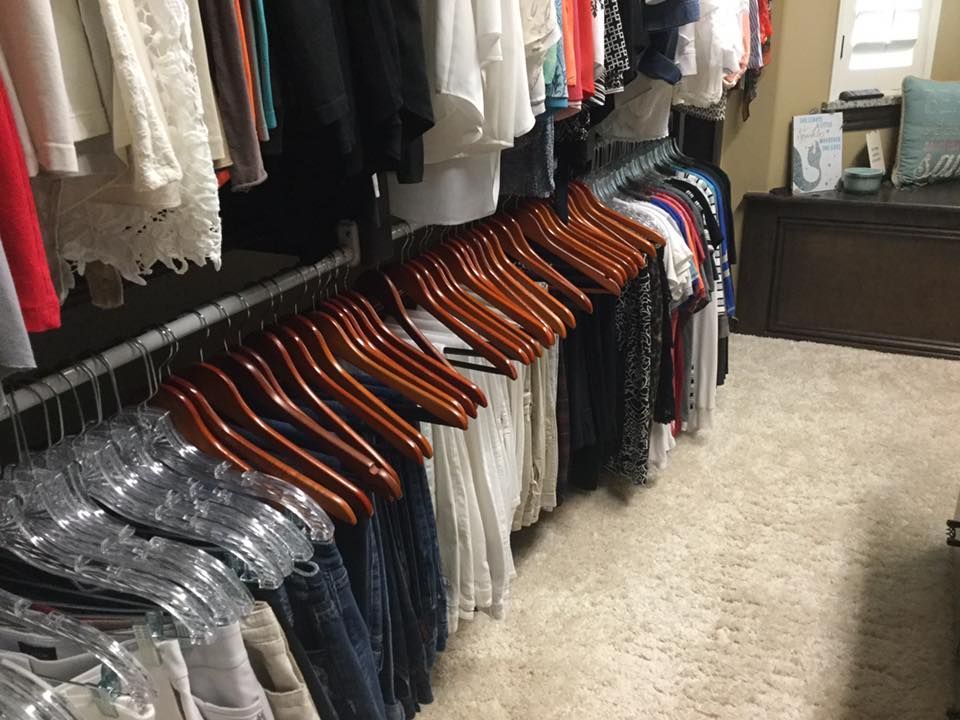 Closet with rows of hanging clothes on various hangers; light carpet and wood trim.