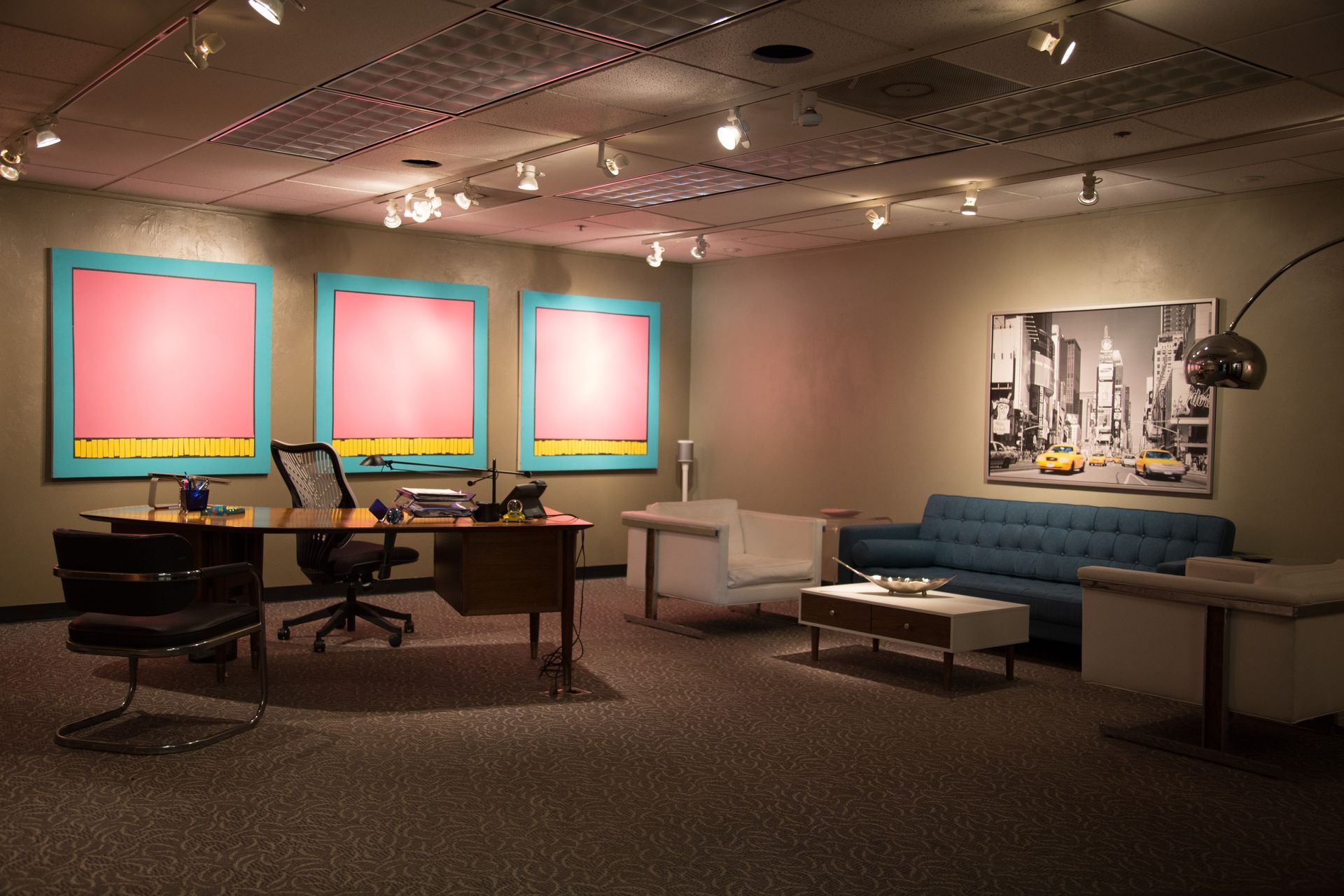 Office interior with a desk, couch, artwork, and modern decor.