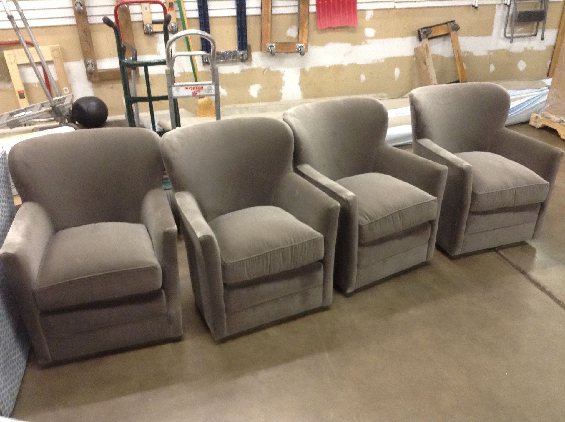 Four upholstered armchairs in a workshop setting, arranged in a row.