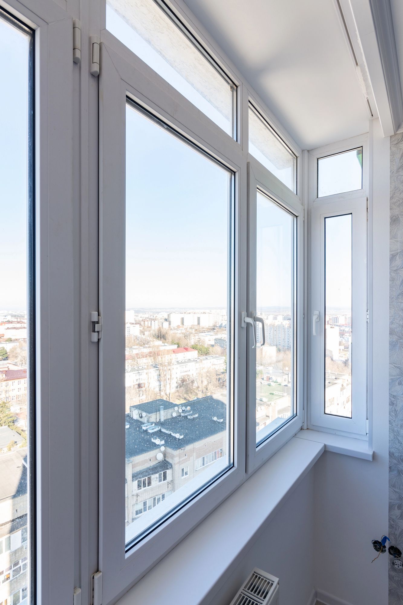 Le finestre con cornice bianca si affacciano sul paesaggio urbano in una giornata di sole.
