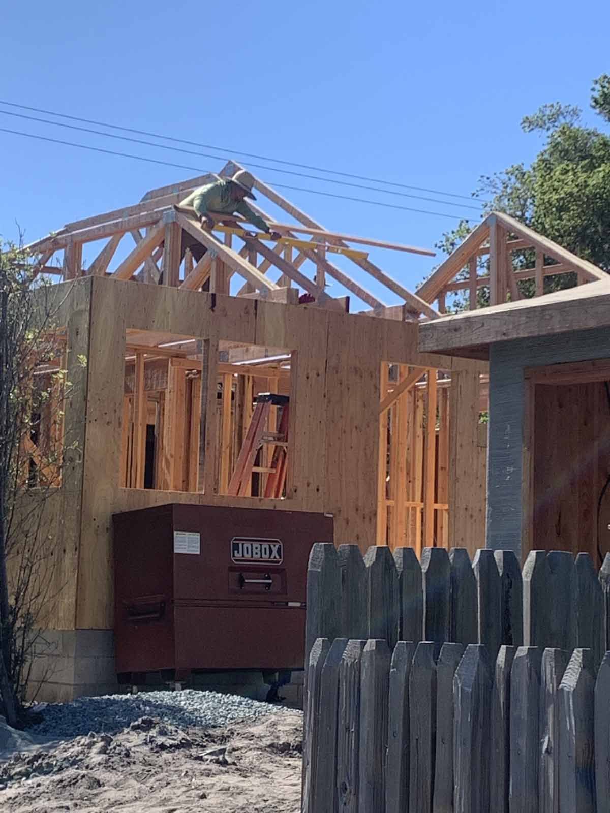 A house is being built with a fence in the foreground.