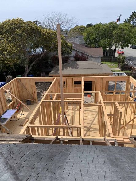 A house is being built with wooden beams and a roof.