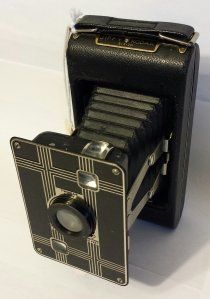 An old camera is sitting on a white table.