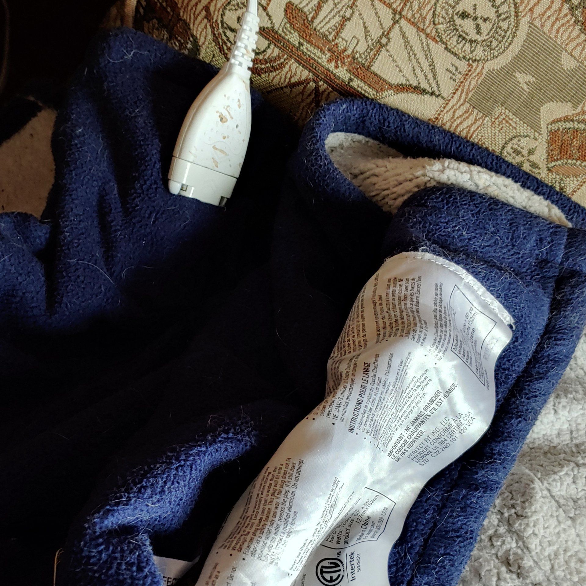 A blue blanket with a cord attached to it is laying on a bed.