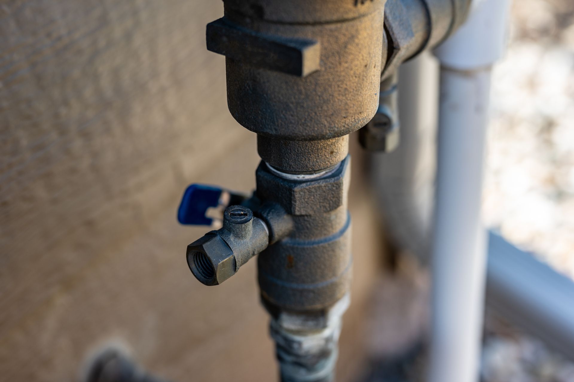 Close-up of a rusted outdoor pipe valve with a blue lever handle