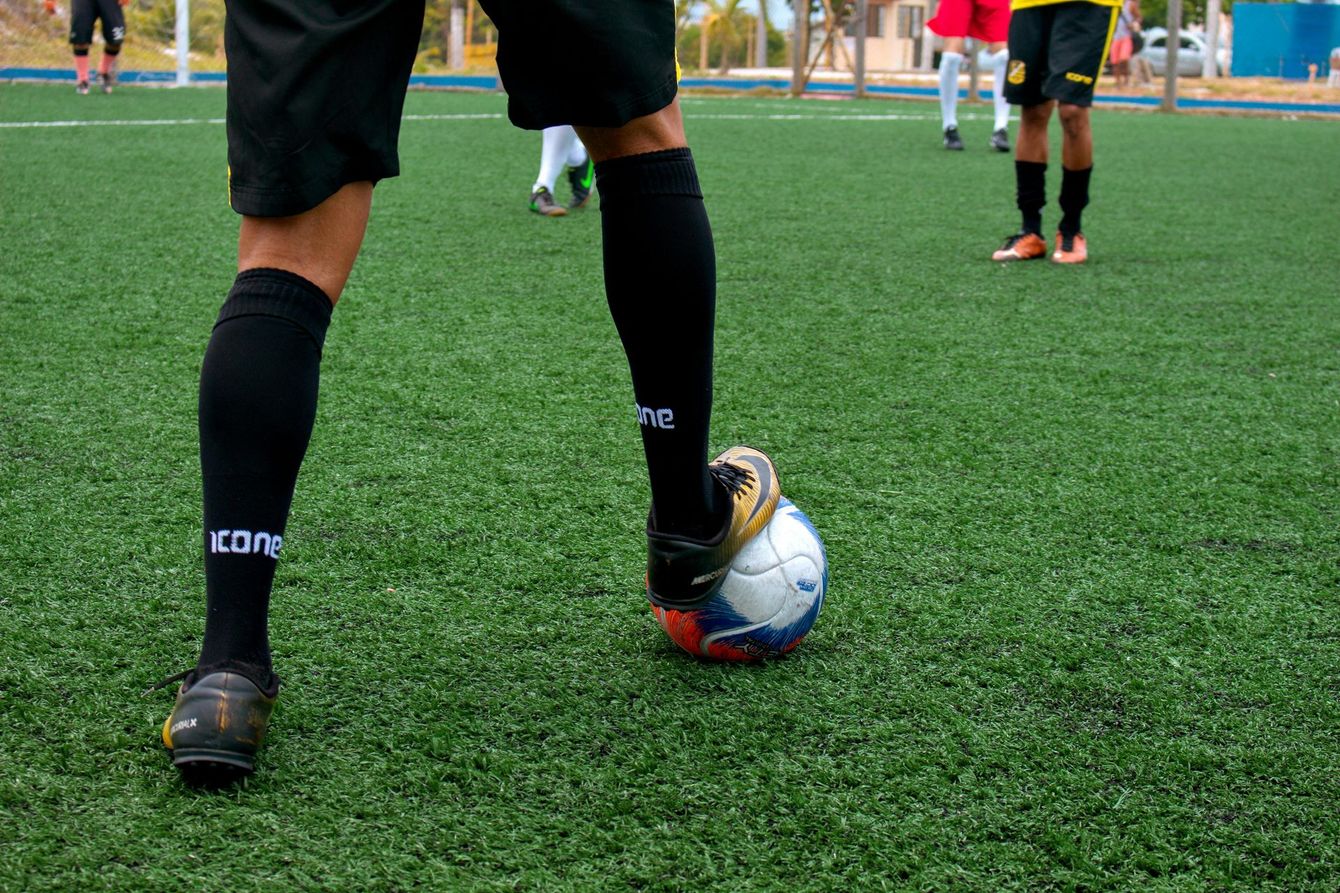 Soccer players on artificial turf passing the ball. 