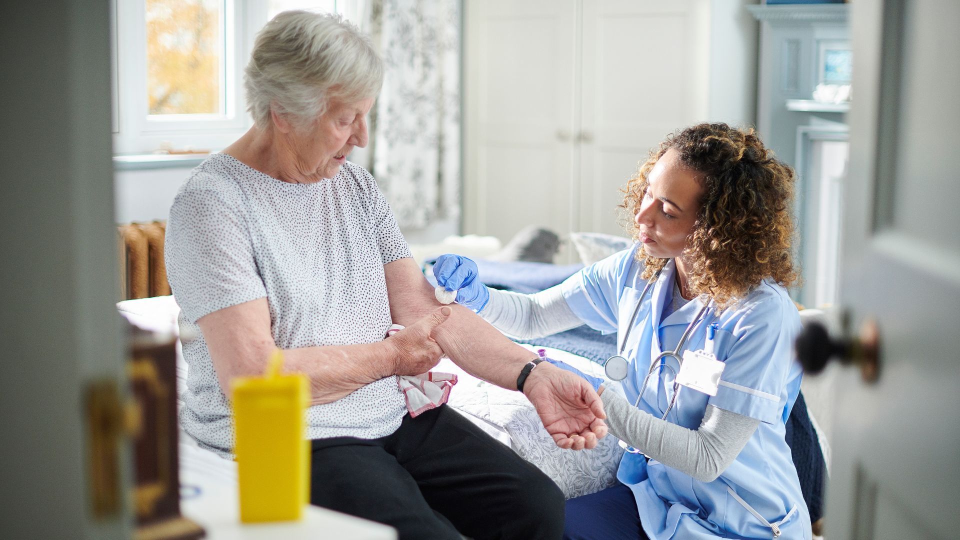 Nurse giving an elderly patient a shot in the arm; indoor setting, sterile syringe, arm visible, close up.