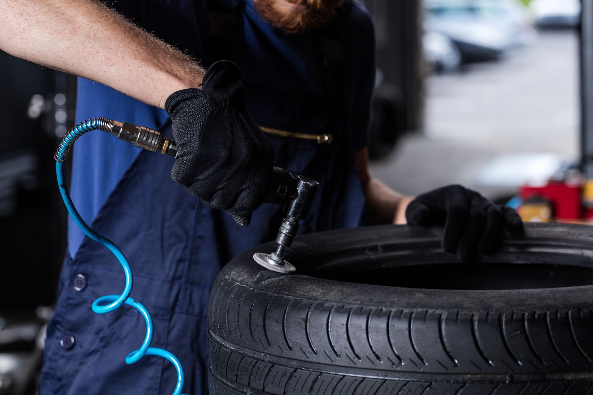 Mechanic using an impact wrench to remove a car tire in a garage
