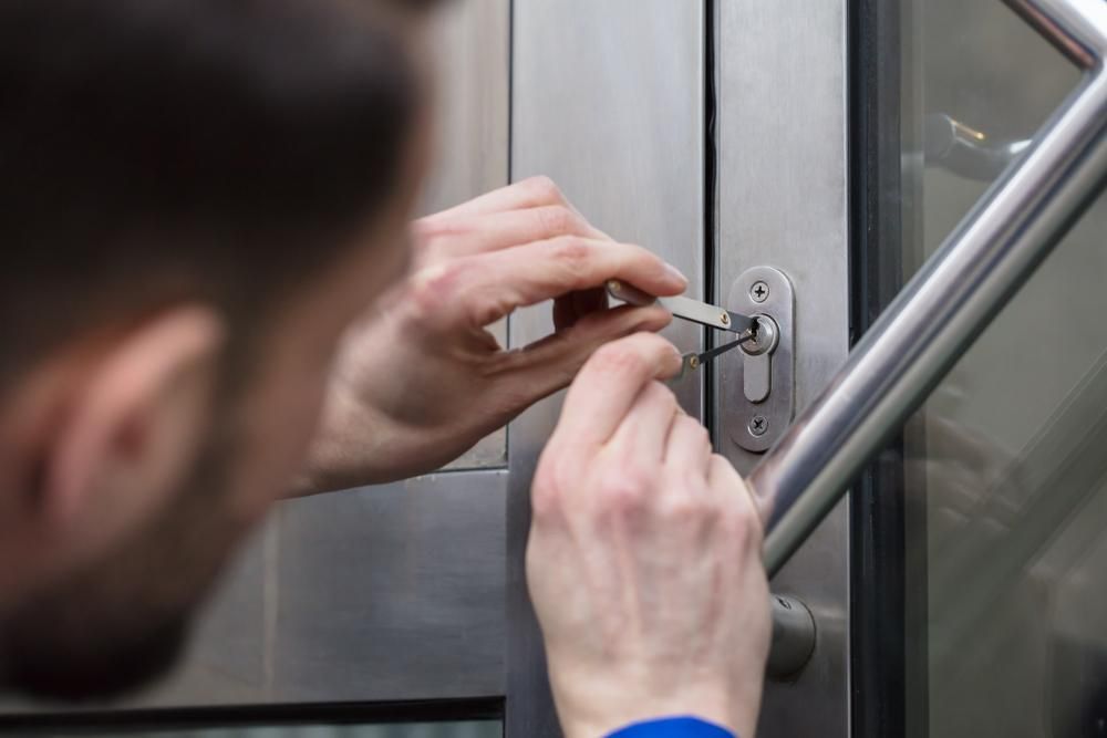 A Man is Locking a Door With a Key — FNQ Locksmiths In Mossman, QLD
