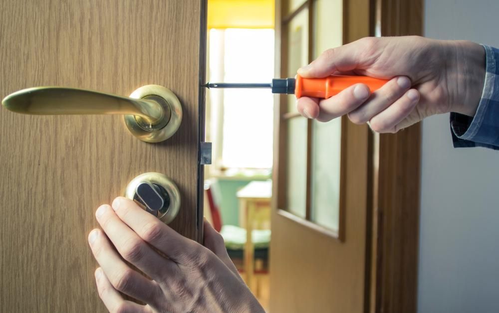 A Person is Fixing a Door With a Screwdriver — FNQ Locksmiths In Smithfield, QLD