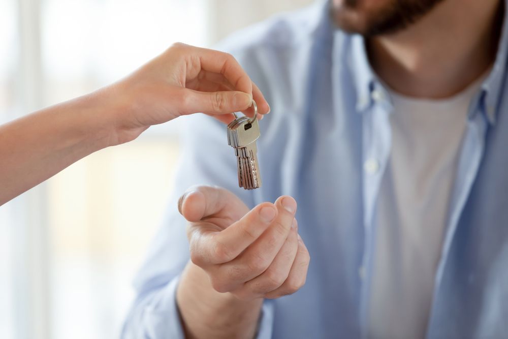 A Man Is Being Handed A Set Of Keys By A Woman — FNQ Locksmiths in Wonga Beach, QLD