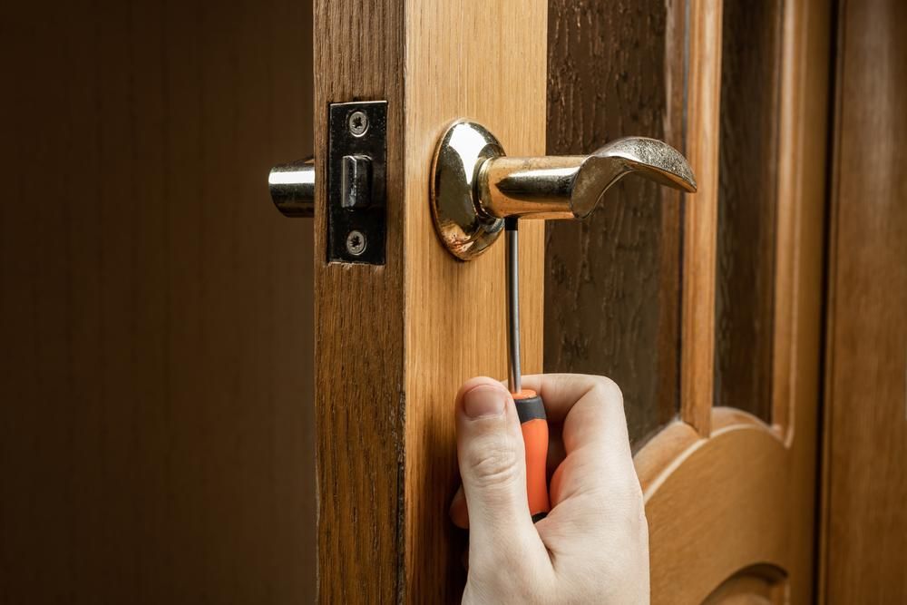 A Person is Fixing a Door Handle With a Screwdriver — FNQ Locksmiths In Mossman, QLD