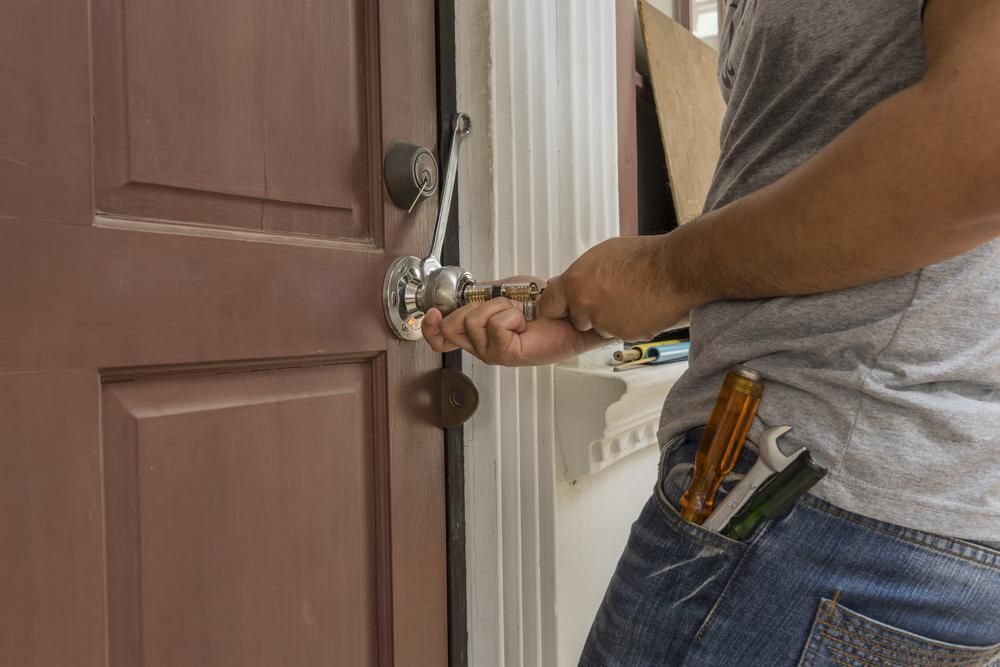 A Man is Fixing a Door With a Wrench — FNQ Locksmiths In Trinity Beach, QLD