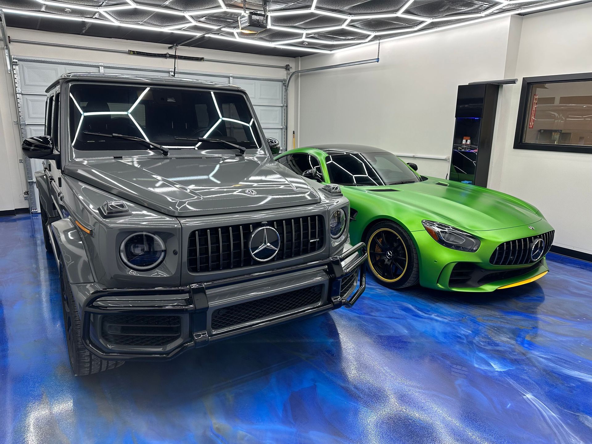 Two custom sports cars, a gray SUV and a lime green coupe, parked in a modern garage.