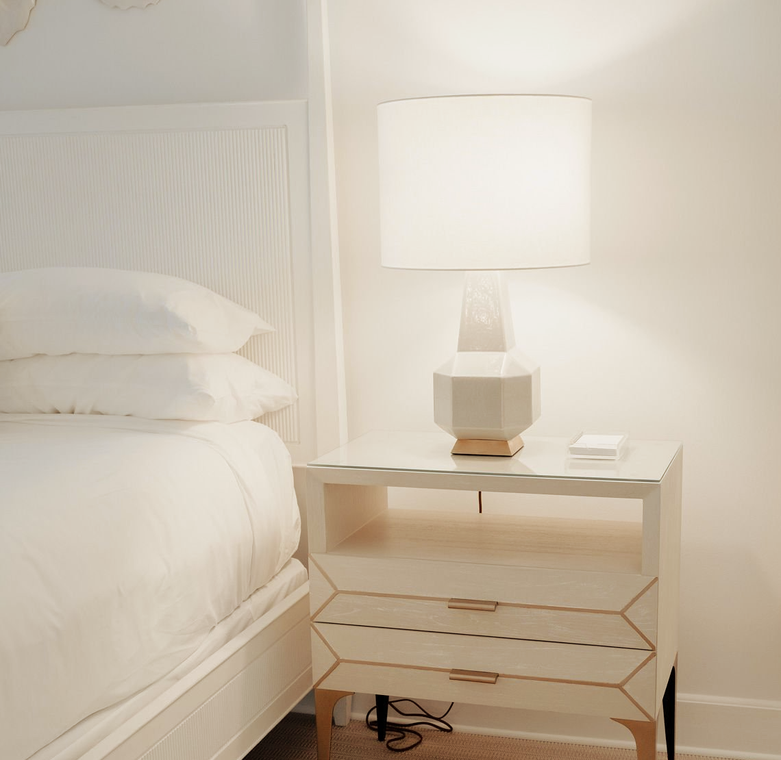 A lamp sits on a nightstand next to a bed