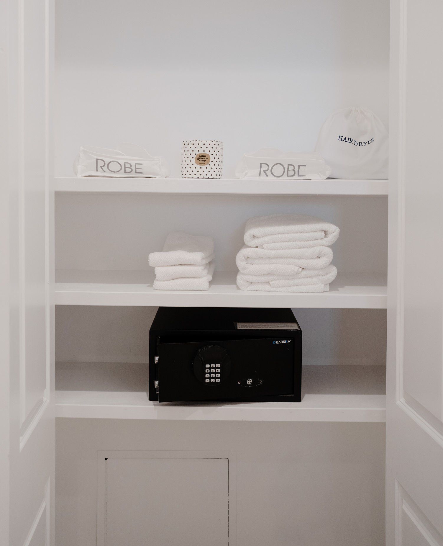 A closet with a safe and towels on the shelves