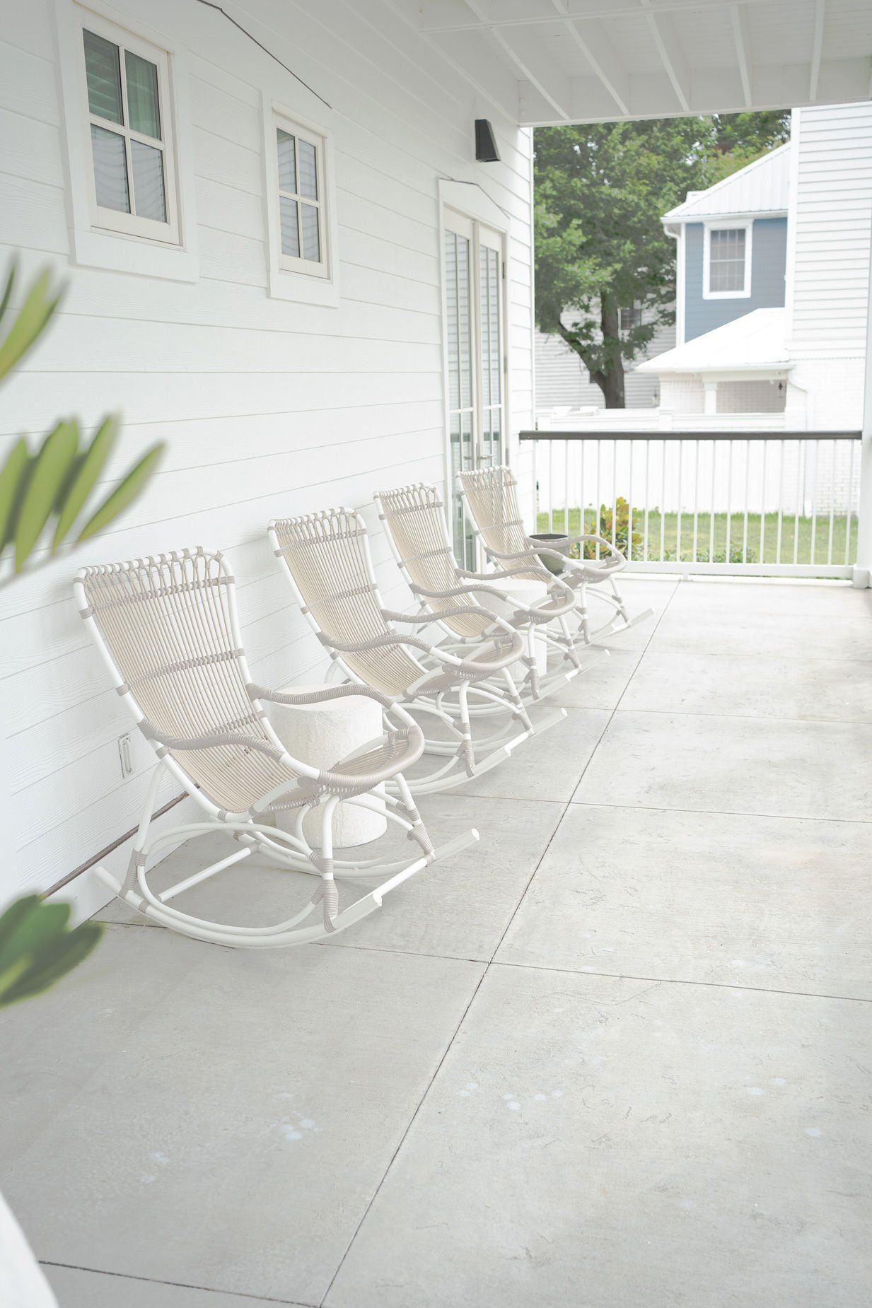 A row of white rocking chairs on a porch