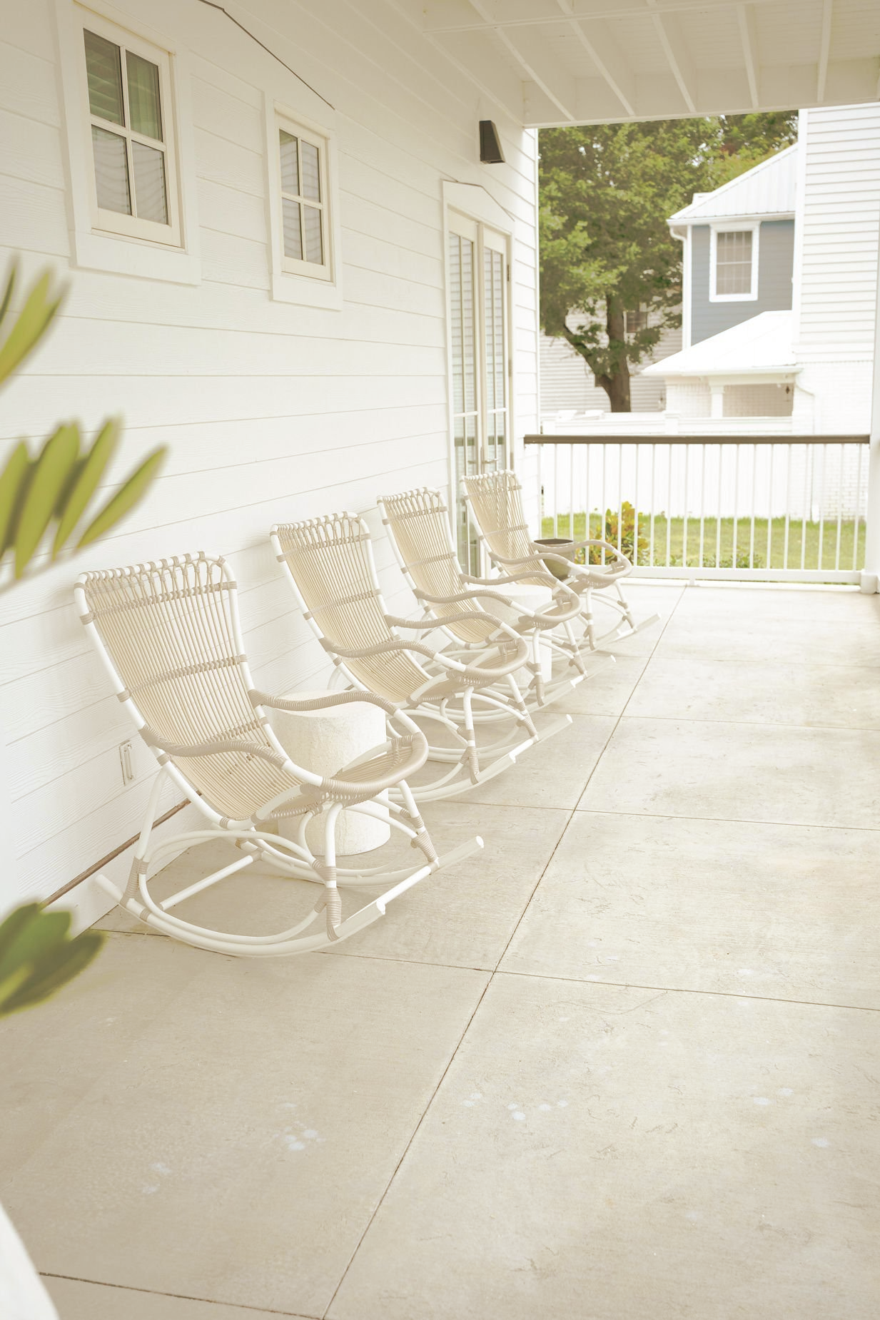 A row of white rocking chairs on a porch