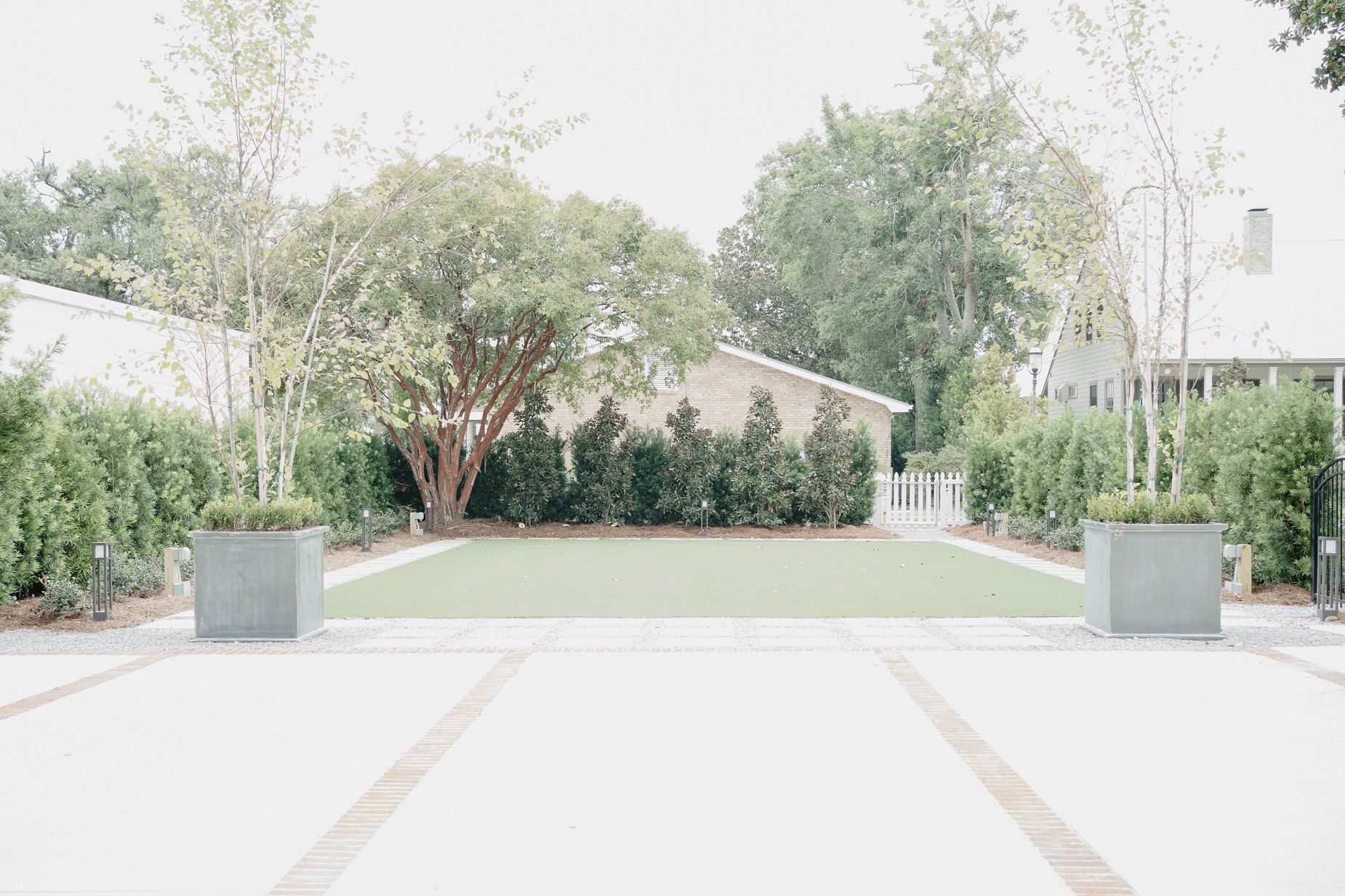 A large lawn with trees and bushes in front of a house.