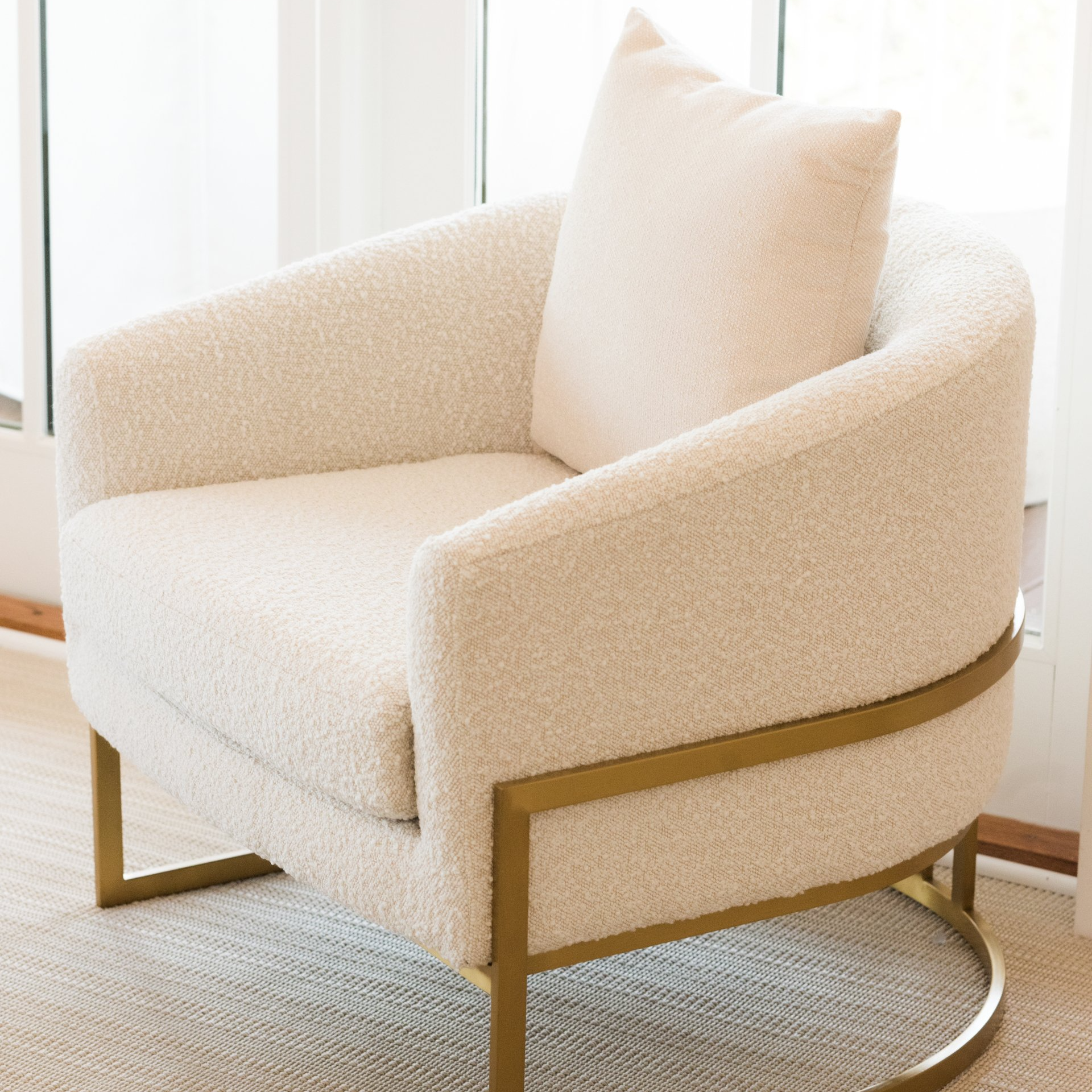 A white chair with a gold frame sits in front of a window