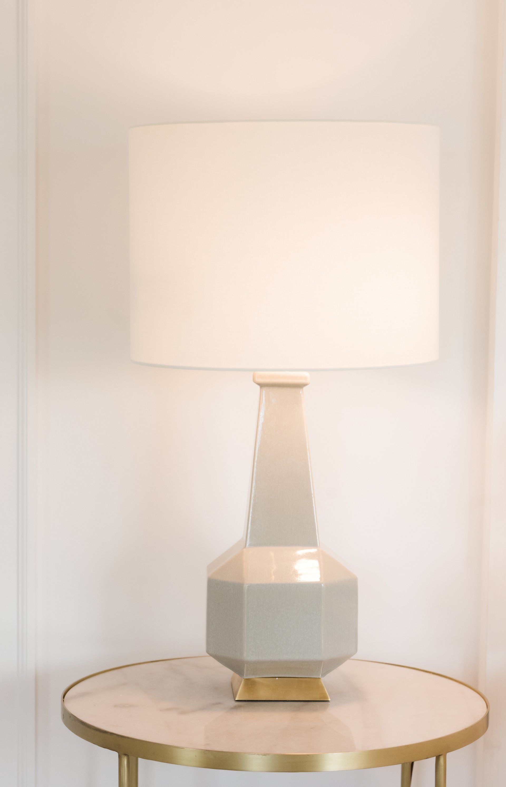 A lamp with a white shade sits on a round table