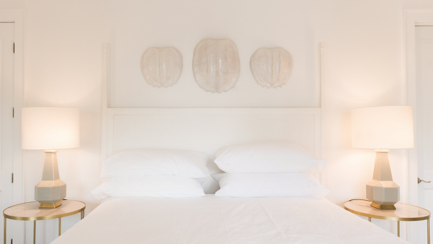 A bedroom with two lamps and a bed with white sheets