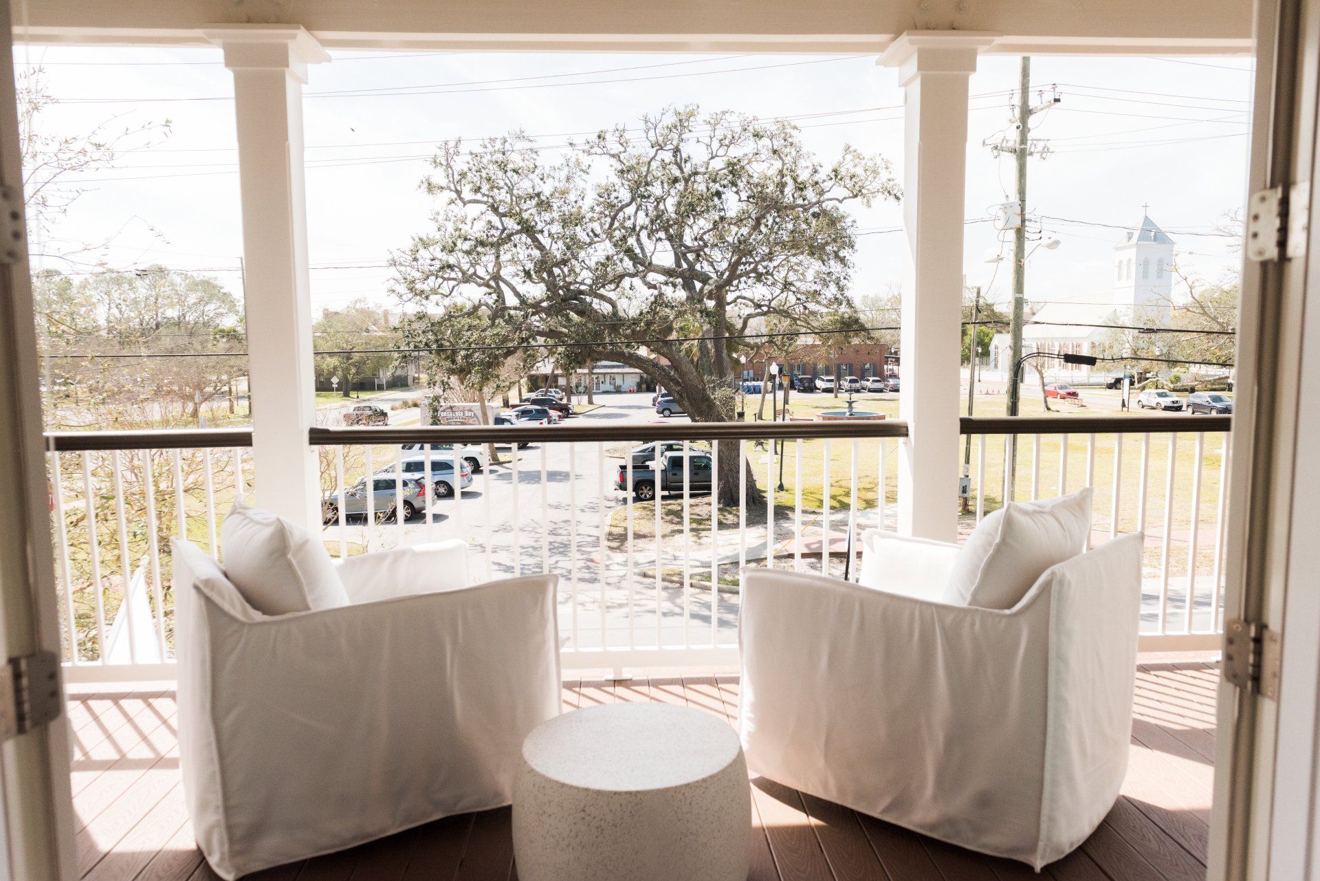 A balcony with two white chairs and a table