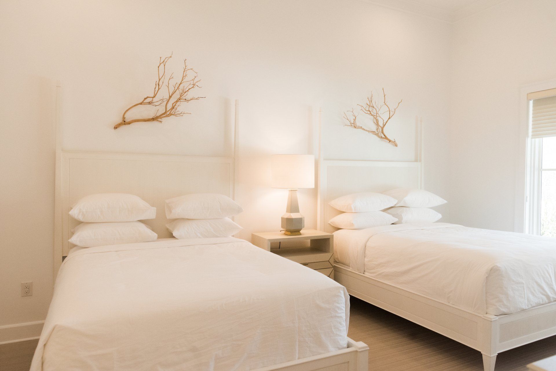 A bedroom with two beds and a lamp on the nightstand