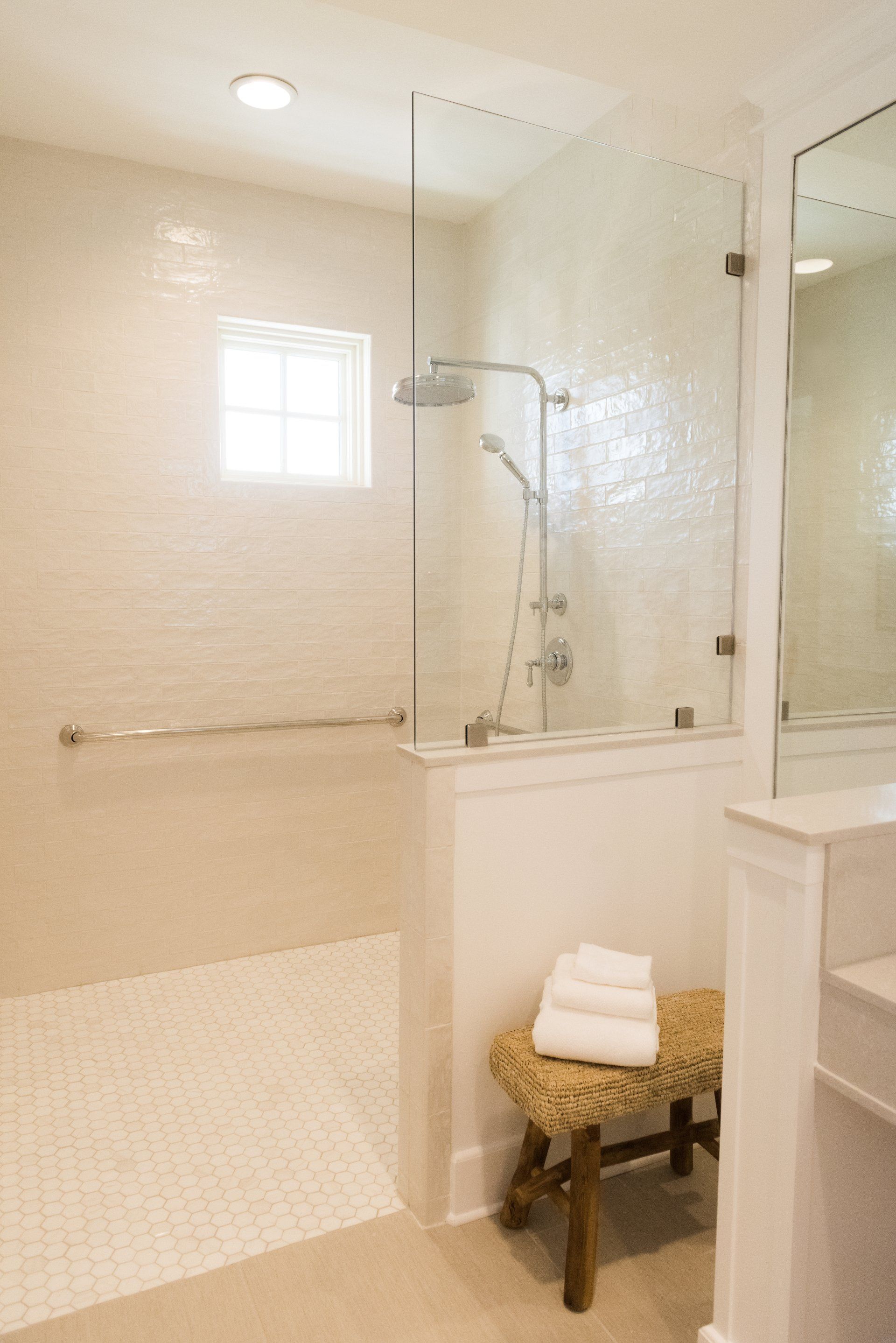 A bathroom with a walk in shower and a stool