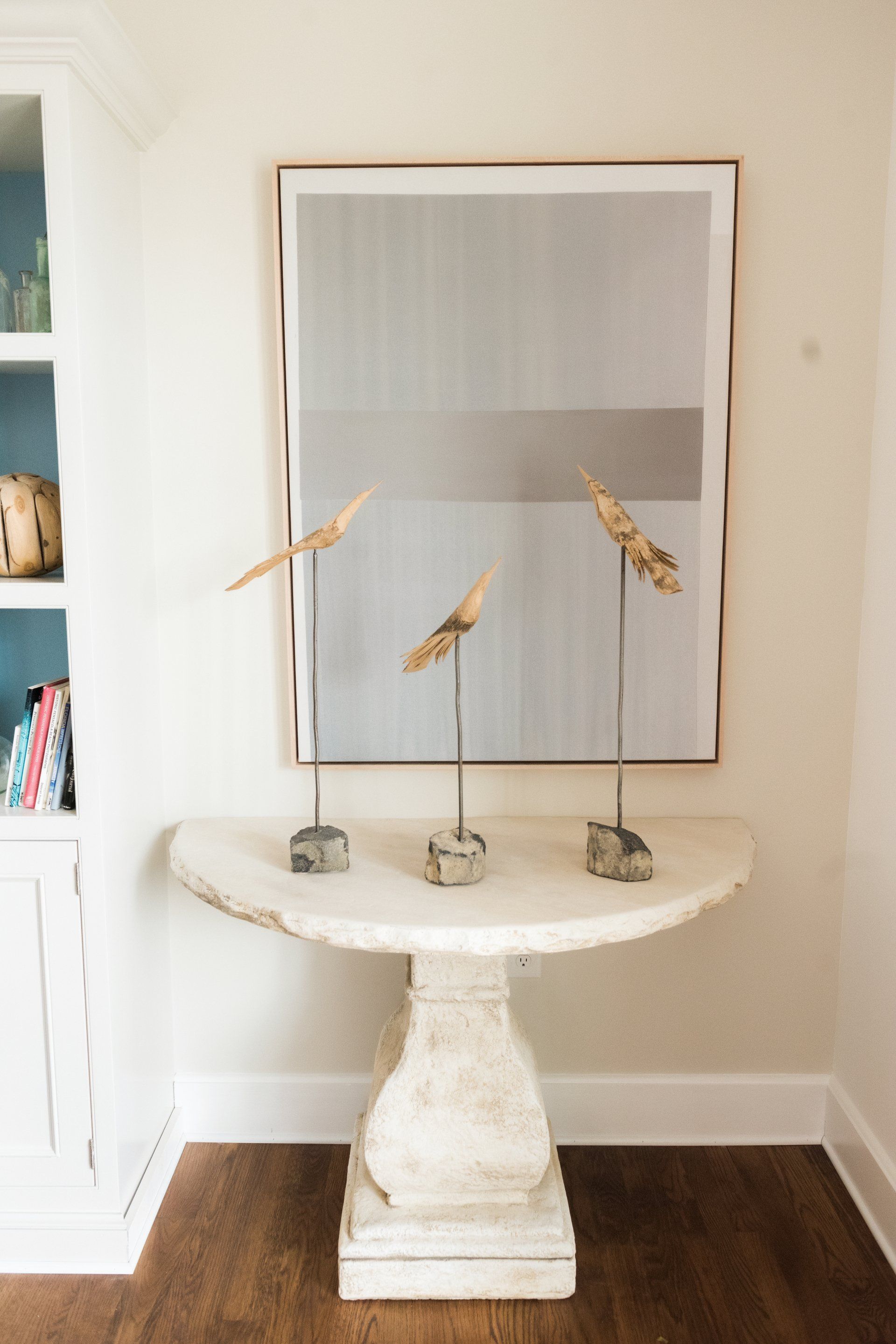 Three birds are sitting on a table under a painting